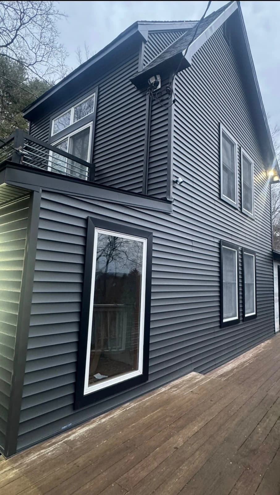 Modern two story home with charcoal siding and illuminated exterior architectural light fixture